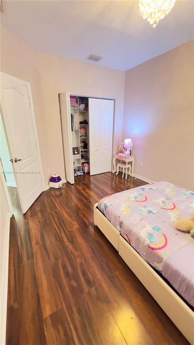 bedroom featuring wood finished floors, visible vents, a closet, and baseboards
