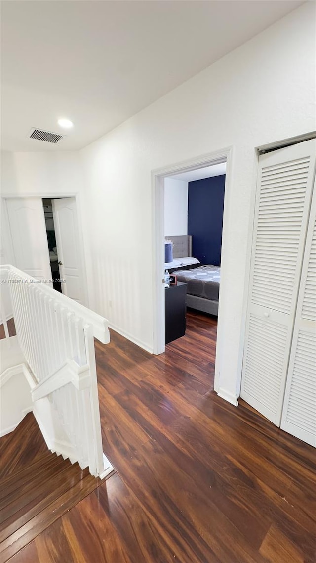 corridor featuring visible vents, baseboards, and wood finished floors