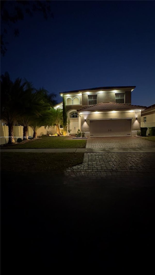 view of front of home featuring a tiled roof, decorative driveway, a garage, and fence