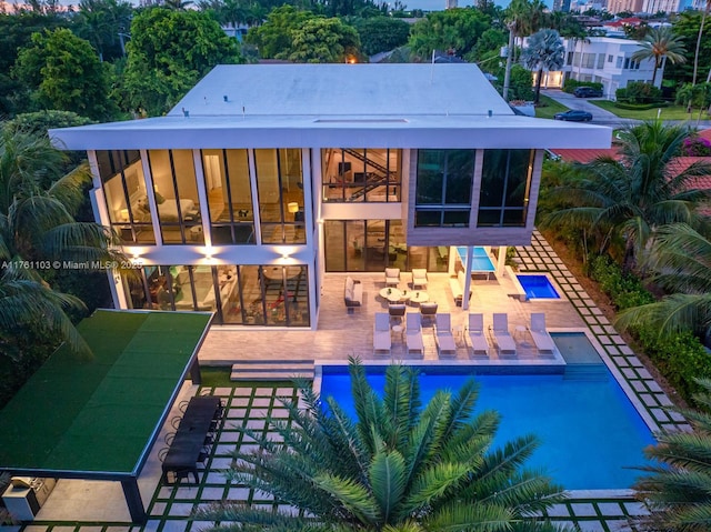 back of house with a patio area, an infinity pool, and a sunroom