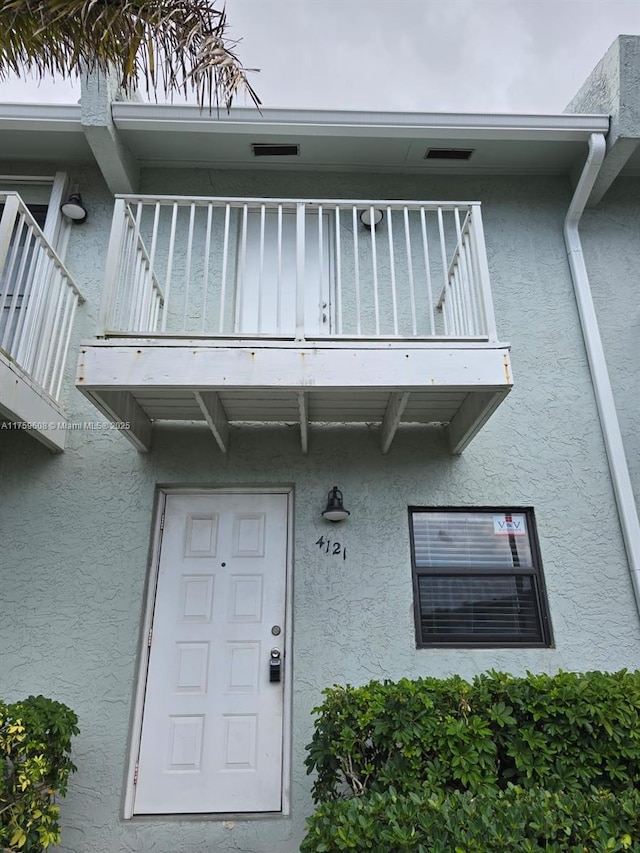 property entrance featuring stucco siding and a balcony