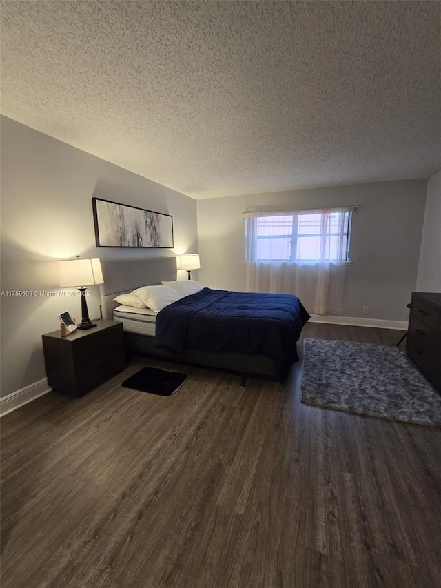 bedroom featuring baseboards, a textured ceiling, and wood finished floors