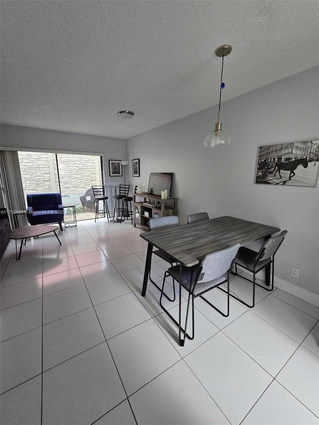 dining space with light tile patterned floors, baseboards, and a textured ceiling