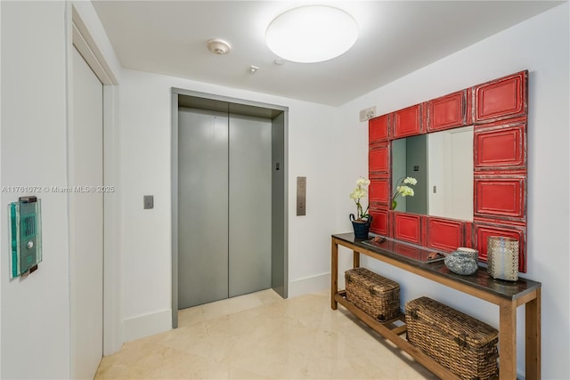 hallway featuring baseboards, elevator, and marble finish floor