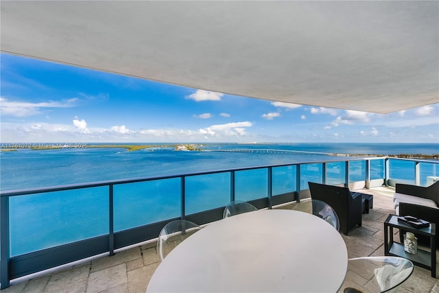 balcony with outdoor dining area, a water view, and outdoor lounge area