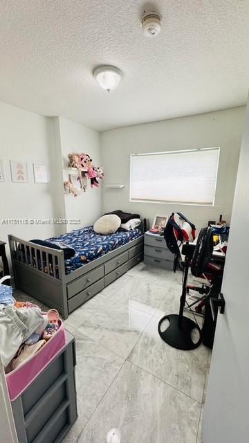 bedroom featuring marble finish floor and a textured ceiling