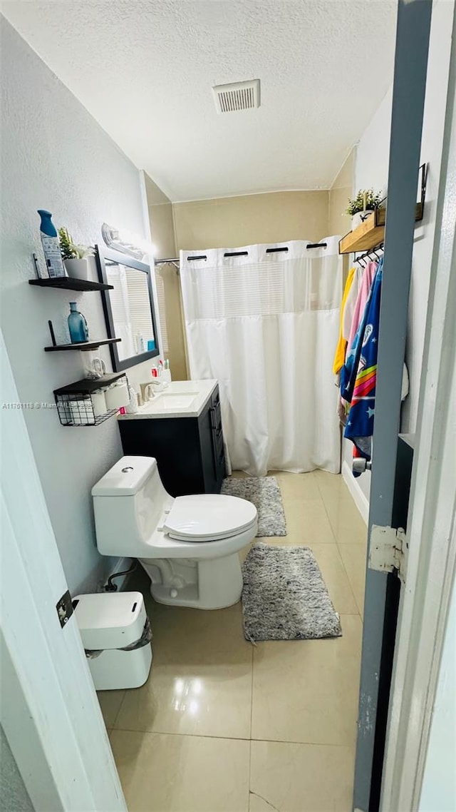 bathroom with visible vents, toilet, curtained shower, a textured ceiling, and tile patterned flooring