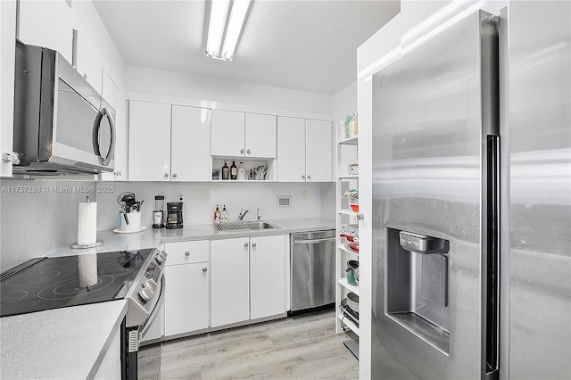 kitchen with open shelves, a sink, light countertops, white cabinets, and appliances with stainless steel finishes