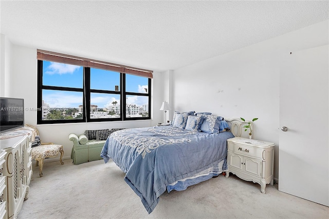 bedroom featuring light colored carpet and a textured ceiling