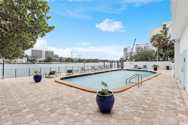 community pool with a water view, fence, a city view, and a patio area