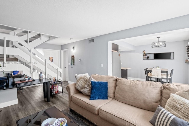 living room with visible vents, baseboards, stairs, an inviting chandelier, and wood finished floors