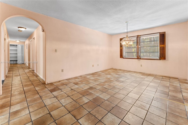 spare room featuring light tile patterned floors, a notable chandelier, arched walkways, and a textured ceiling