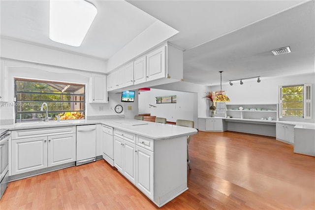 kitchen with a peninsula, a sink, light countertops, dishwasher, and open floor plan