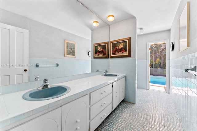 bathroom with double vanity, tile walls, tile patterned floors, and a sink