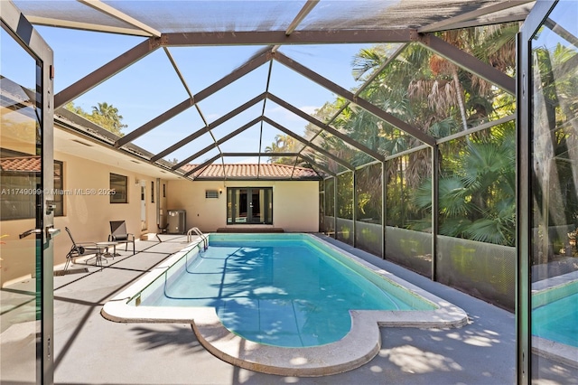 pool with french doors, glass enclosure, and a patio area