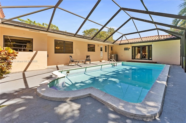 pool featuring glass enclosure, central AC, and a patio