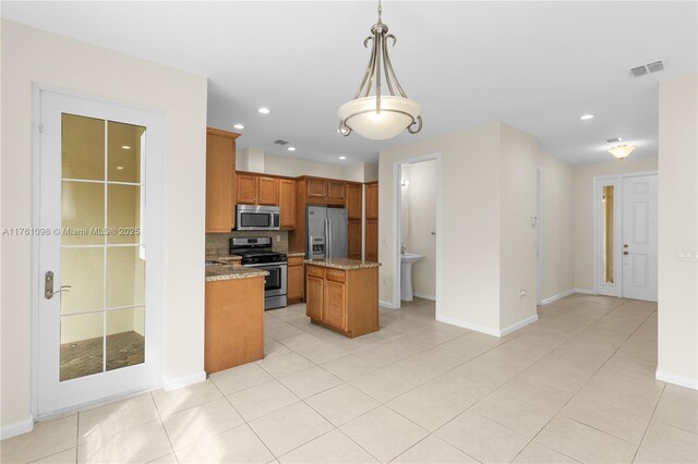 kitchen featuring visible vents, a kitchen island, decorative light fixtures, brown cabinets, and appliances with stainless steel finishes