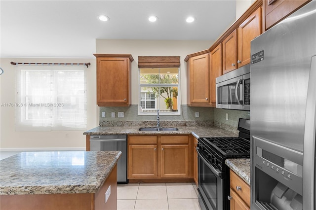 kitchen featuring a sink, light stone countertops, appliances with stainless steel finishes, and light tile patterned flooring