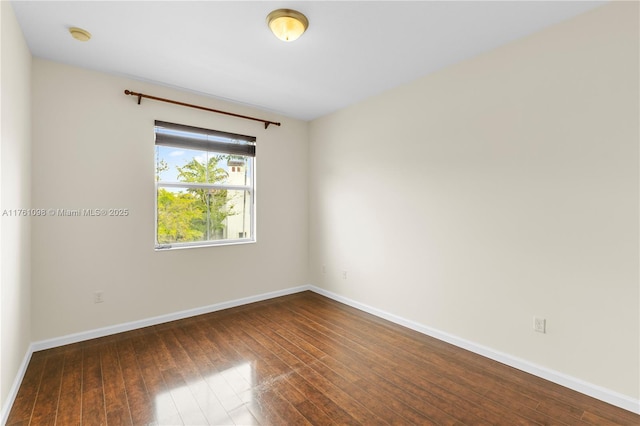 empty room featuring dark wood-style floors and baseboards