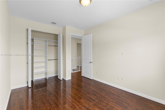 unfurnished bedroom with a closet, baseboards, visible vents, and hardwood / wood-style floors