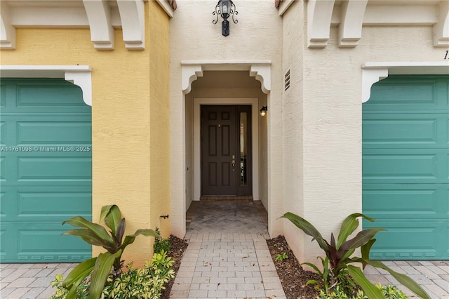 doorway to property featuring a garage and stucco siding