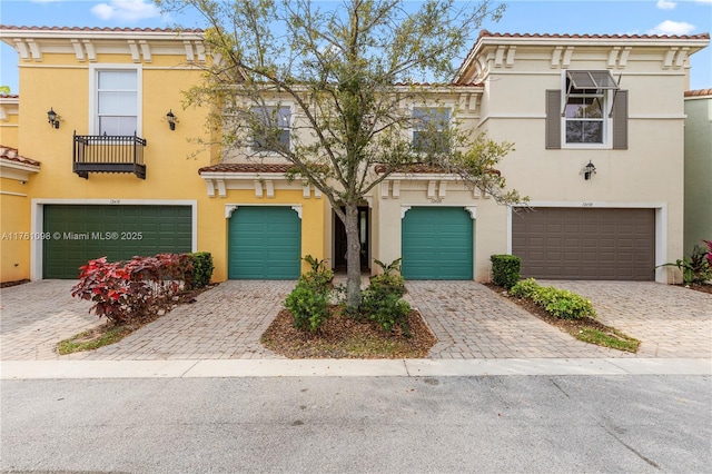 view of front of property with stucco siding, an attached garage, a tile roof, and driveway