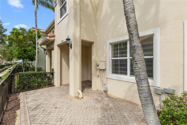 view of exterior entry with stucco siding and a patio