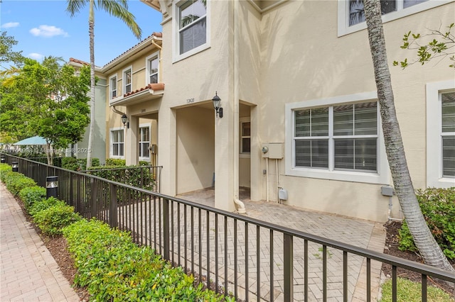 entrance to property featuring a patio, fence, and stucco siding