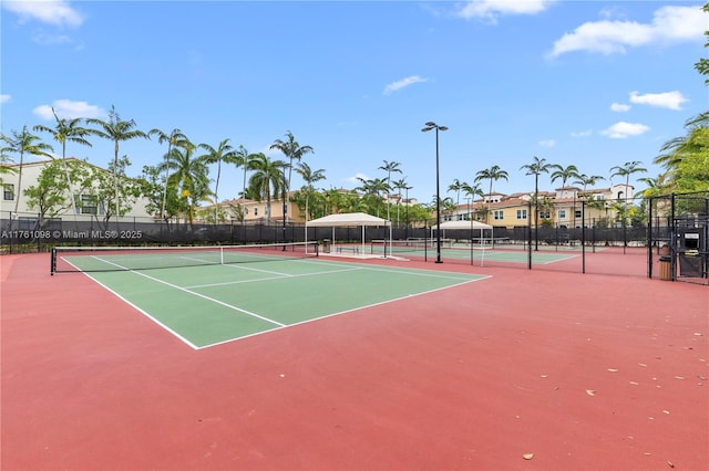 view of tennis court with community basketball court and fence