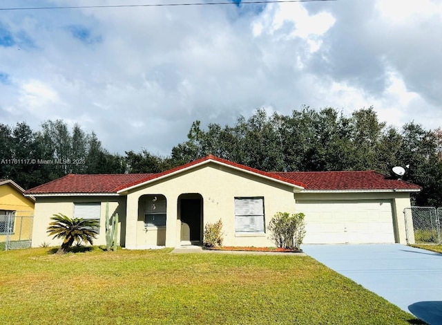 mediterranean / spanish house featuring stucco siding, driveway, fence, a front yard, and a garage