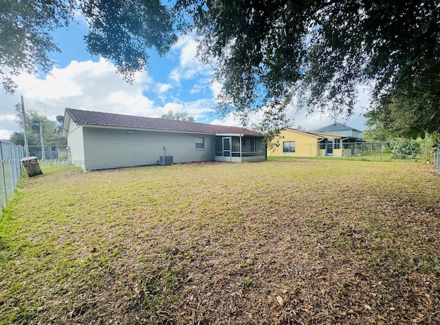 807 Mountbatten Ln, Kissimmee, FL 34758 - back of house featuring a yard, central air condition unit, a fenced backyard, and a sunroom