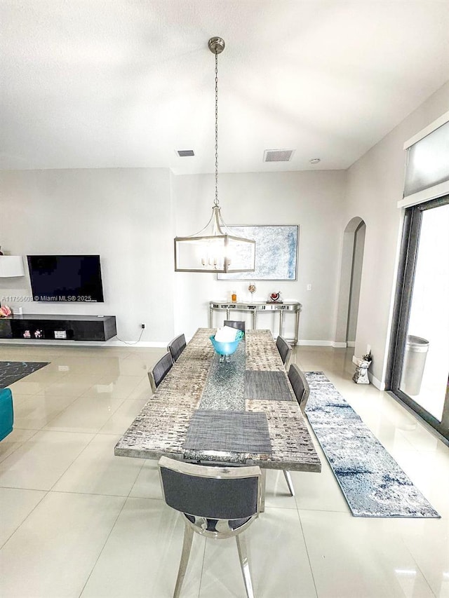 dining area featuring arched walkways, visible vents, tile patterned flooring, and baseboards