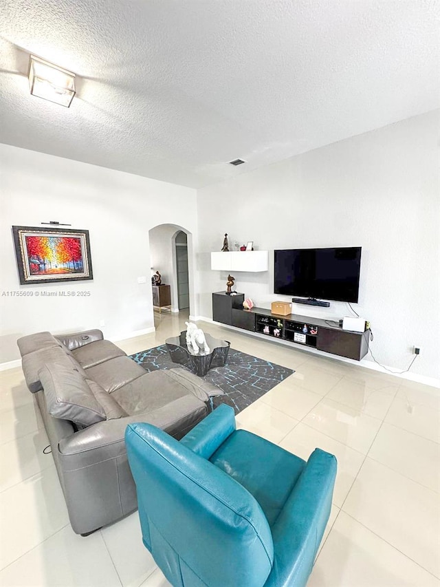 tiled living room featuring visible vents, arched walkways, and a textured ceiling