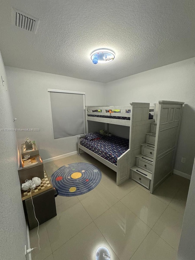 bedroom with visible vents, a textured ceiling, and baseboards