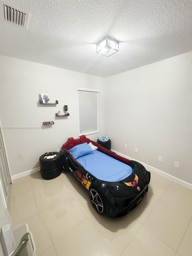 tiled bedroom featuring baseboards, visible vents, and a textured ceiling