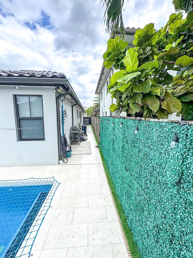 view of side of property with a patio area, stucco siding, and fence