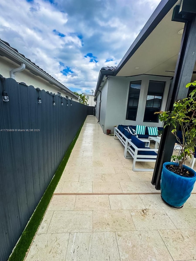 view of property exterior with a patio area, stucco siding, an outdoor hangout area, and fence