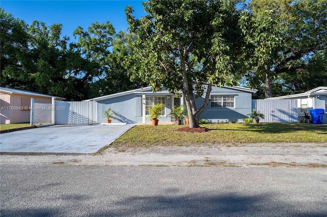 view of front facade with fence, concrete driveway, a front yard, stucco siding, and a gate