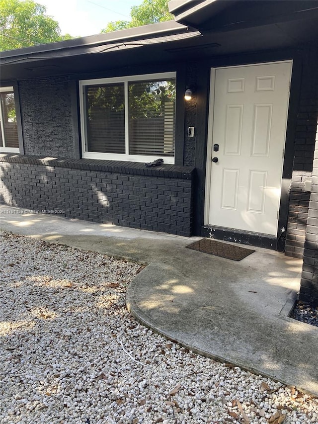 doorway to property featuring brick siding