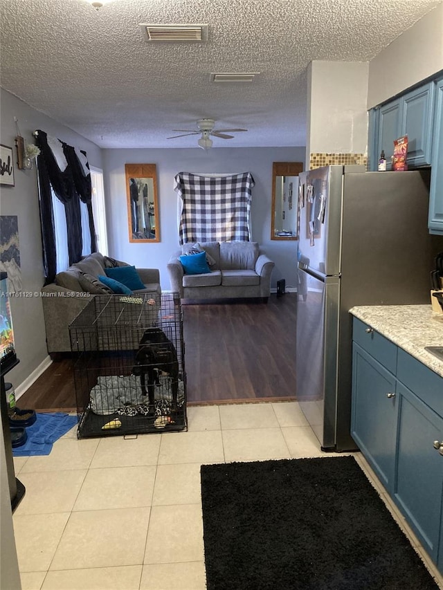 kitchen featuring light tile patterned floors, visible vents, open floor plan, and freestanding refrigerator