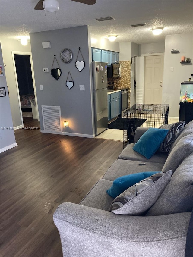 living area with visible vents, a textured ceiling, and wood finished floors