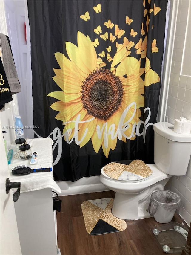 bathroom with toilet, tile walls, a shower with shower curtain, and wood finished floors