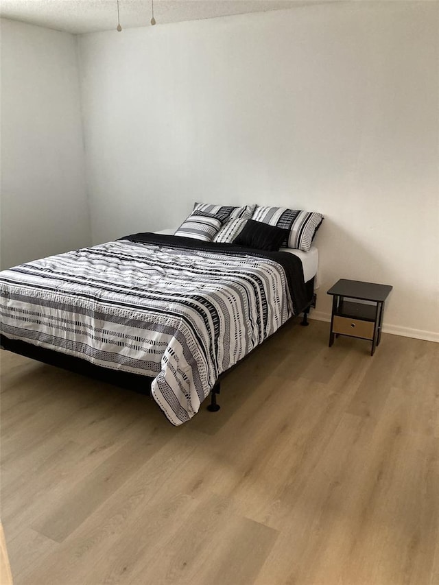 bedroom featuring wood finished floors, baseboards, and a textured ceiling