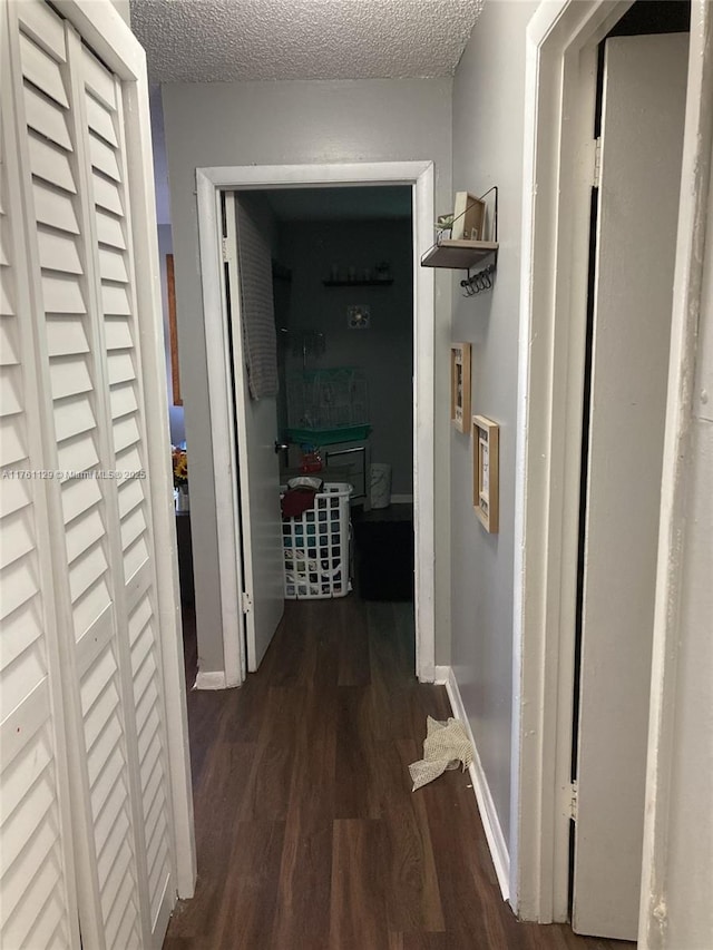 hall featuring wood finished floors, baseboards, and a textured ceiling