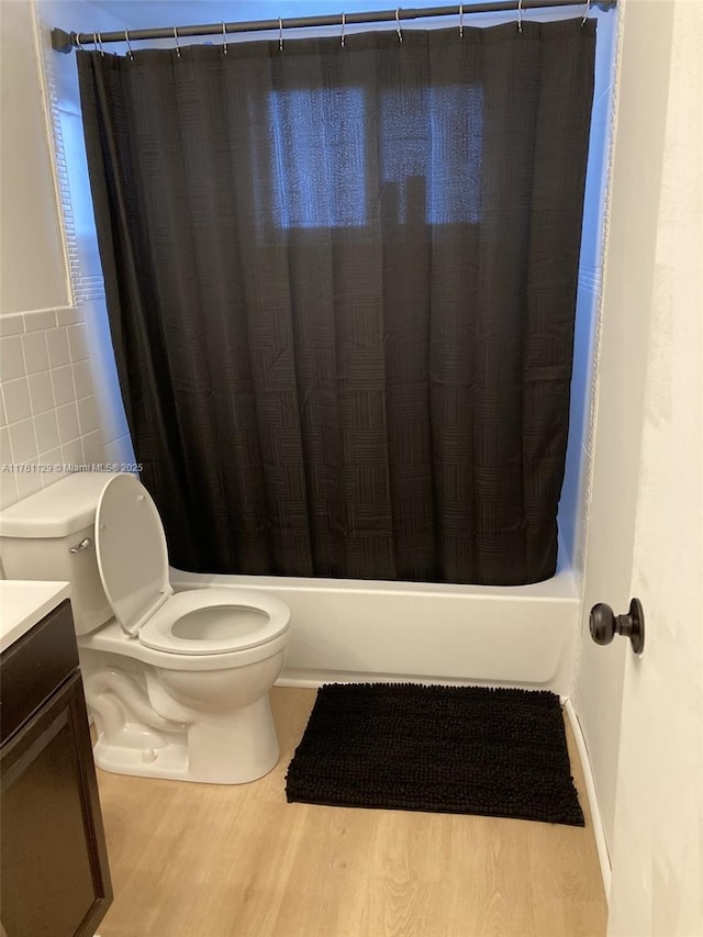 full bath with vanity, wood finished floors, shower / bath combo, tile walls, and toilet