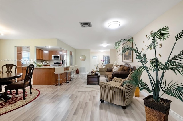living room with light wood-style floors, baseboards, and visible vents