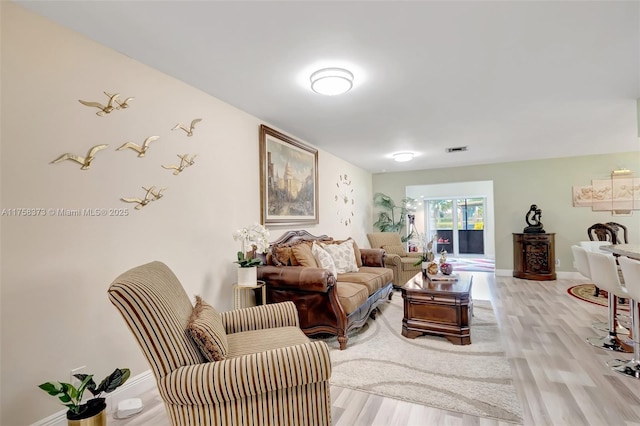 living room featuring visible vents, baseboards, and light wood-style floors