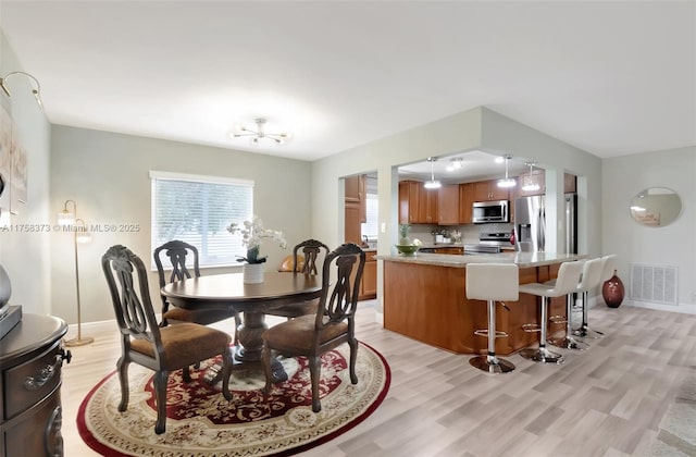 dining room with a chandelier, baseboards, visible vents, and light wood-style floors