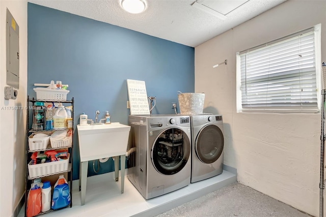 laundry room with laundry area, a textured ceiling, washing machine and dryer, and electric panel