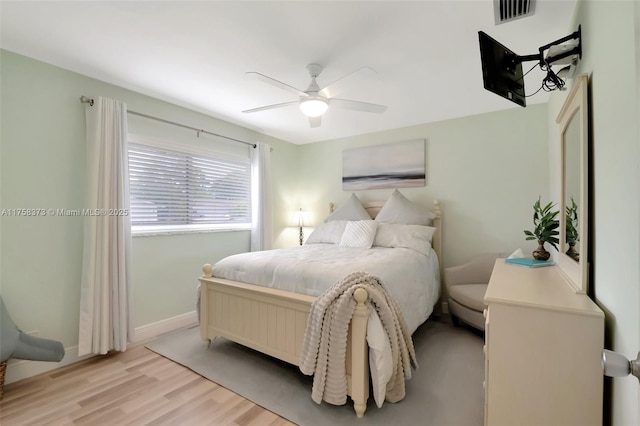 bedroom with light wood-style floors, baseboards, a ceiling fan, and visible vents
